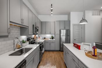 A modern kitchen with a white countertop and grey cabinets. at The Haywood Apartments, Austin, Texas